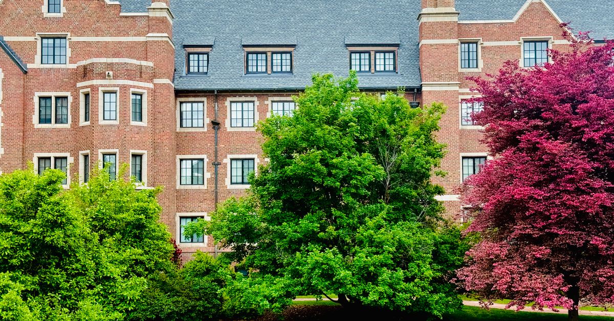 Discover a picturesque brick building surrounded by vibrant green and pink foliage, showcasing classic architecture.