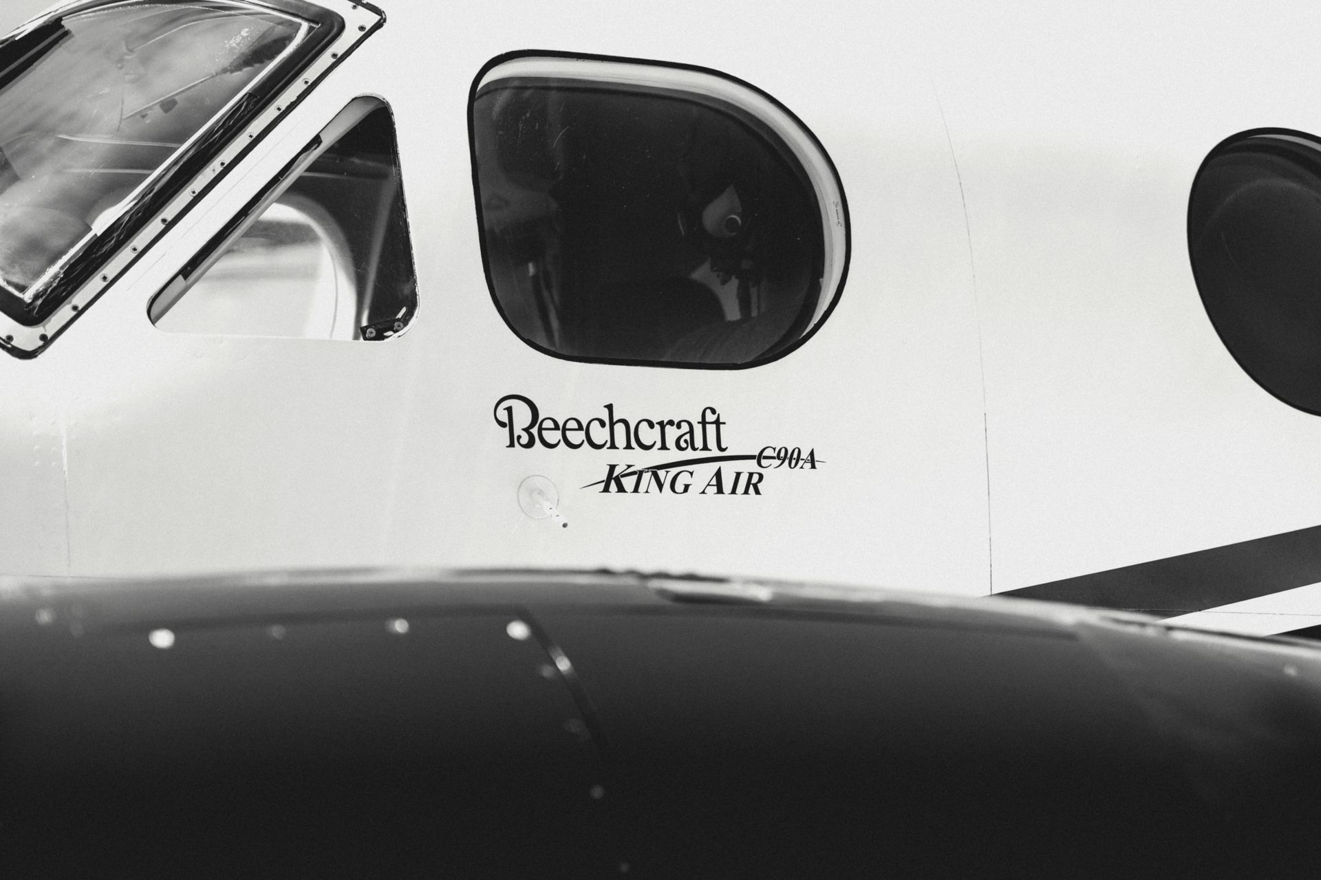 Detailed view of Beechcraft King Air C90A airplane cockpit window in black and white.