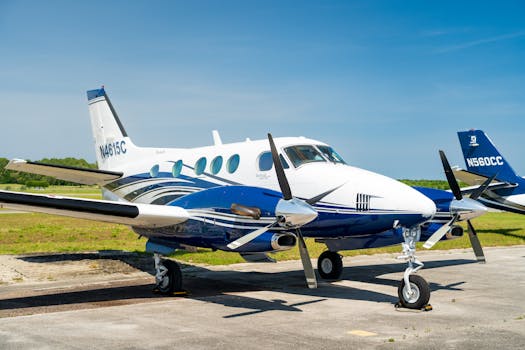 A sleek blue and white private aircraft parked on an airport runway under clear skies.