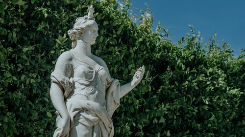Free Marble statue amidst lush greenery on a sunny day, showcasing classic art and serenity. Stock Photo