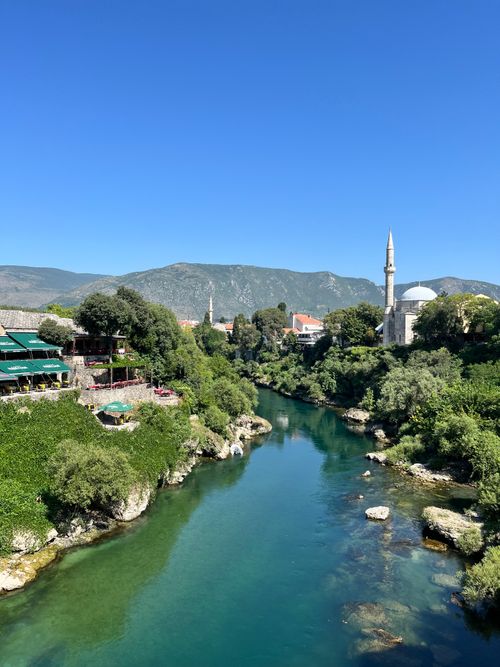 Free Beautiful landscape of Mostar with a river and mosque under a clear blue sky. Stock Photo
