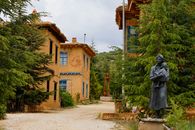 Charming rural houses with a sculpture of a mother and child, surrounded by lush greenery.