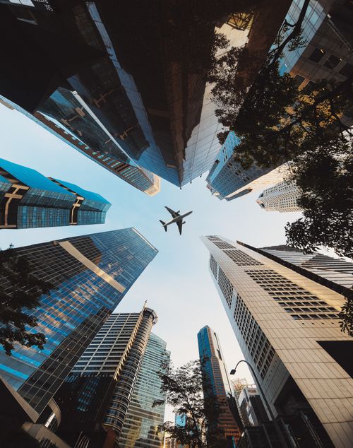 Free A striking perspective of Singapore's skyline with an airplane flying above. Perfect for travel and urban themes. Stock Photo