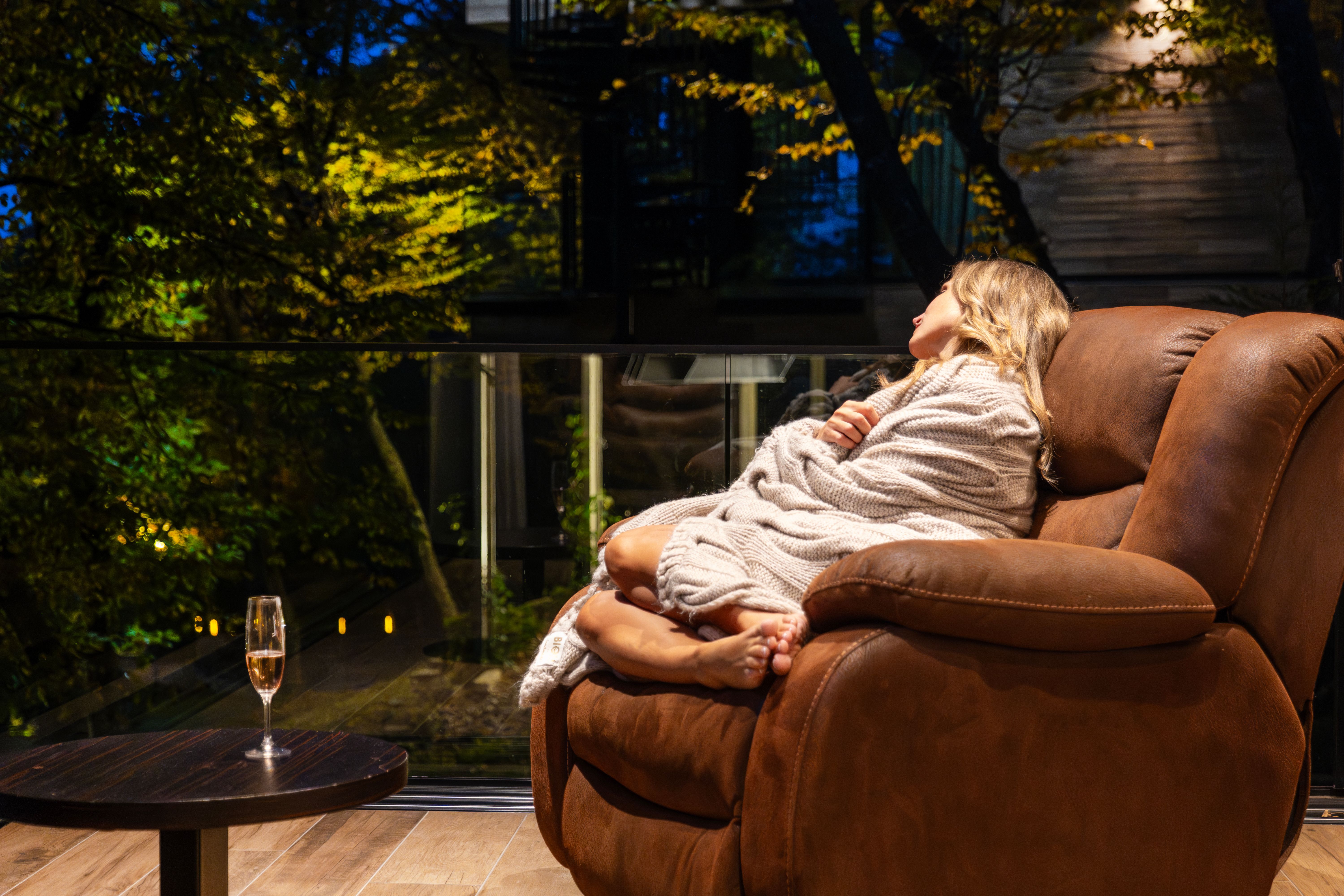 Une femme se détend sur un balcon à Tbilissi, en Géorgie, enveloppée dans une couverture, profitant de la soirée sereine.
