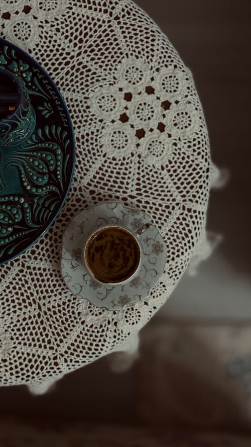 Free Vintage-style coffee cup on lace tablecloth. Overhead, muted tones for a cozy feel. Stock Photo