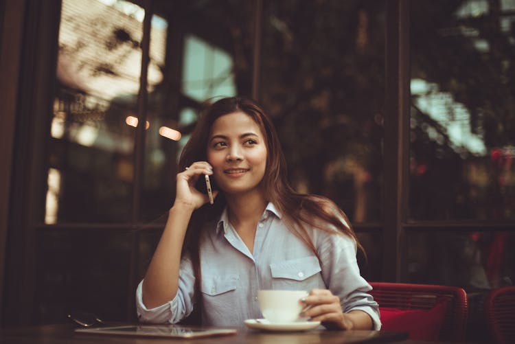 Portrait Of Young Woman Using Mobile Phone In Cafe