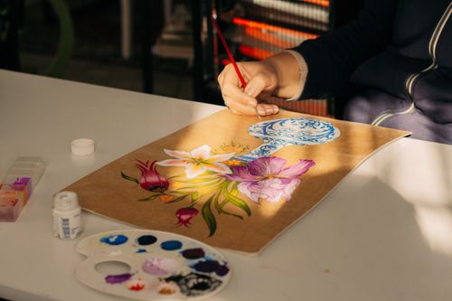 Free A person painting a vibrant floral design on paper with watercolors. Stock Photo