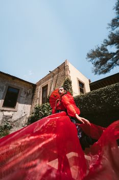 Dramatic shot of a woman in a flowing red gown against an old building, Leon, Mexico.