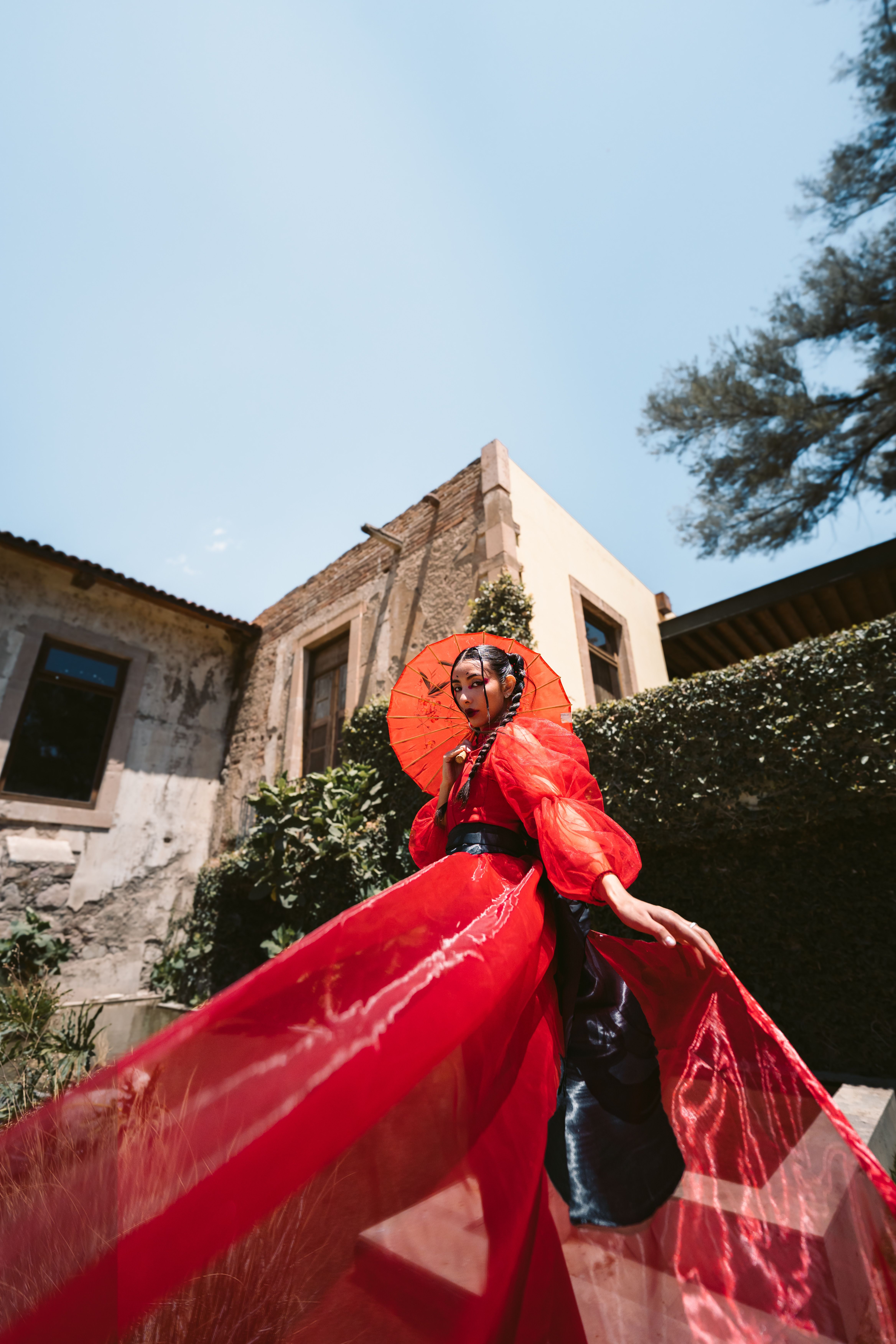 Elegant woman in traditional attire with red parasol in Leon, Mexico.