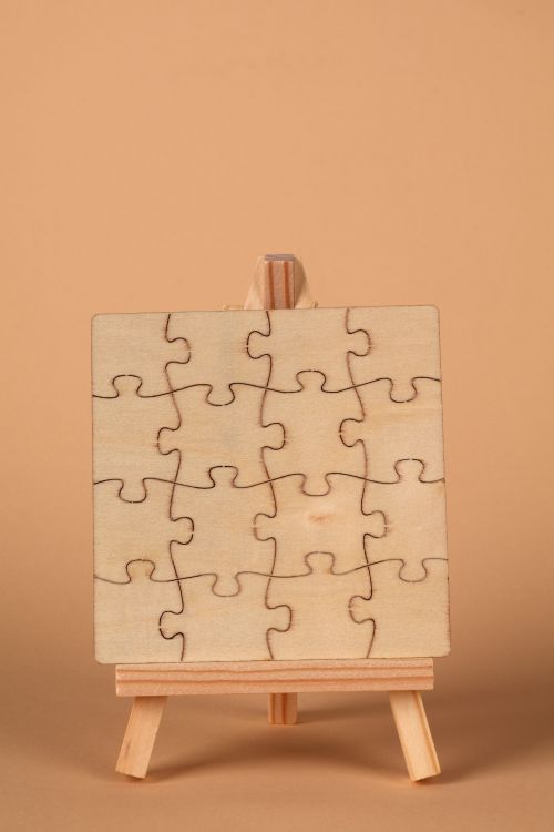 Free A minimalist wooden puzzle placed on a small easel, photographed against a soft brown backdrop. Stock Photo
