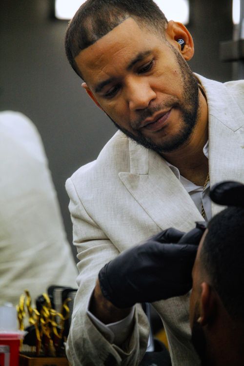 Free A skilled barber in a white suit precisely trims a client's hair in a modern barbershop. Stock Photo