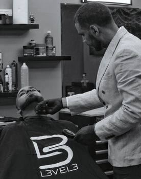 Barber expertly shaves a client's beard in a modern barbershop setting.