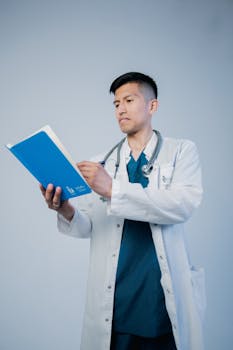 A young male doctor reviewing medical records wearing a stethoscope and lab coat.