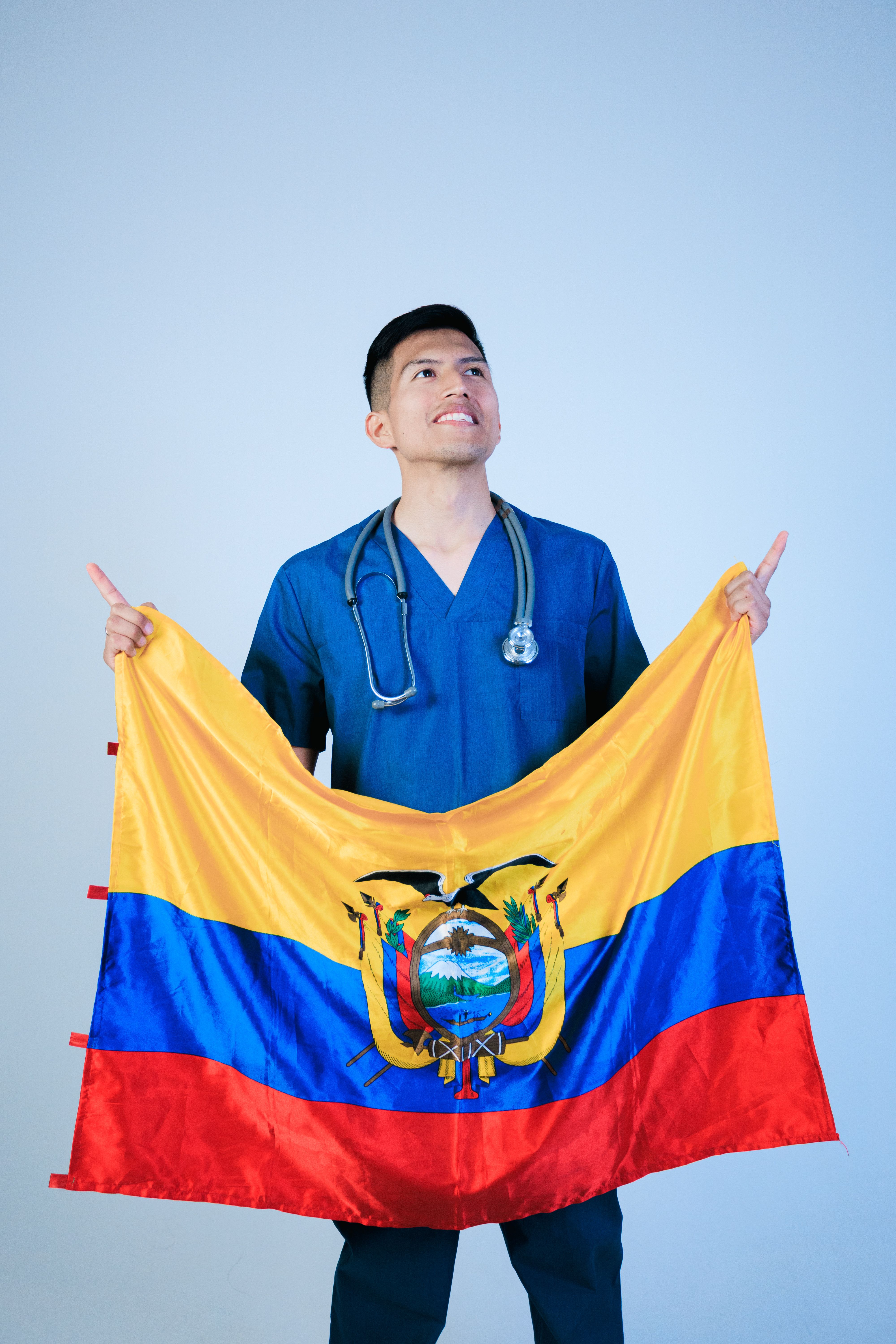 Smiling nurse holding Ecuador flag, representing healthcare and national pride.