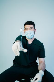 Medical practitioner in mask and gloves holding surgical instrument, emphasizing focus and precision.