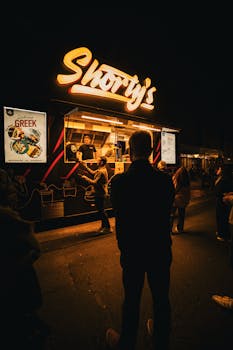A vibrant night scene of a street food stall 'Shorty's' with neon signs in Sydney, Australia.