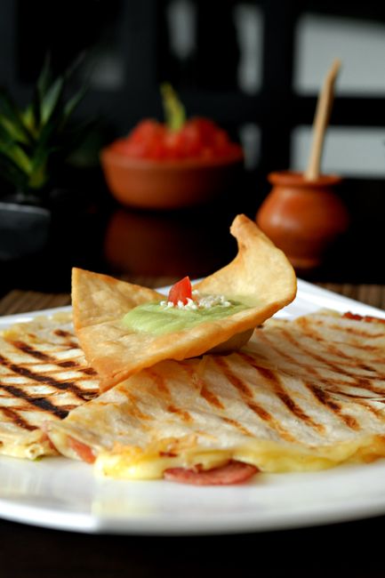 A folded tortilla with melted cheese oozing at the edge, browned and crisped on a flat-top griddle.