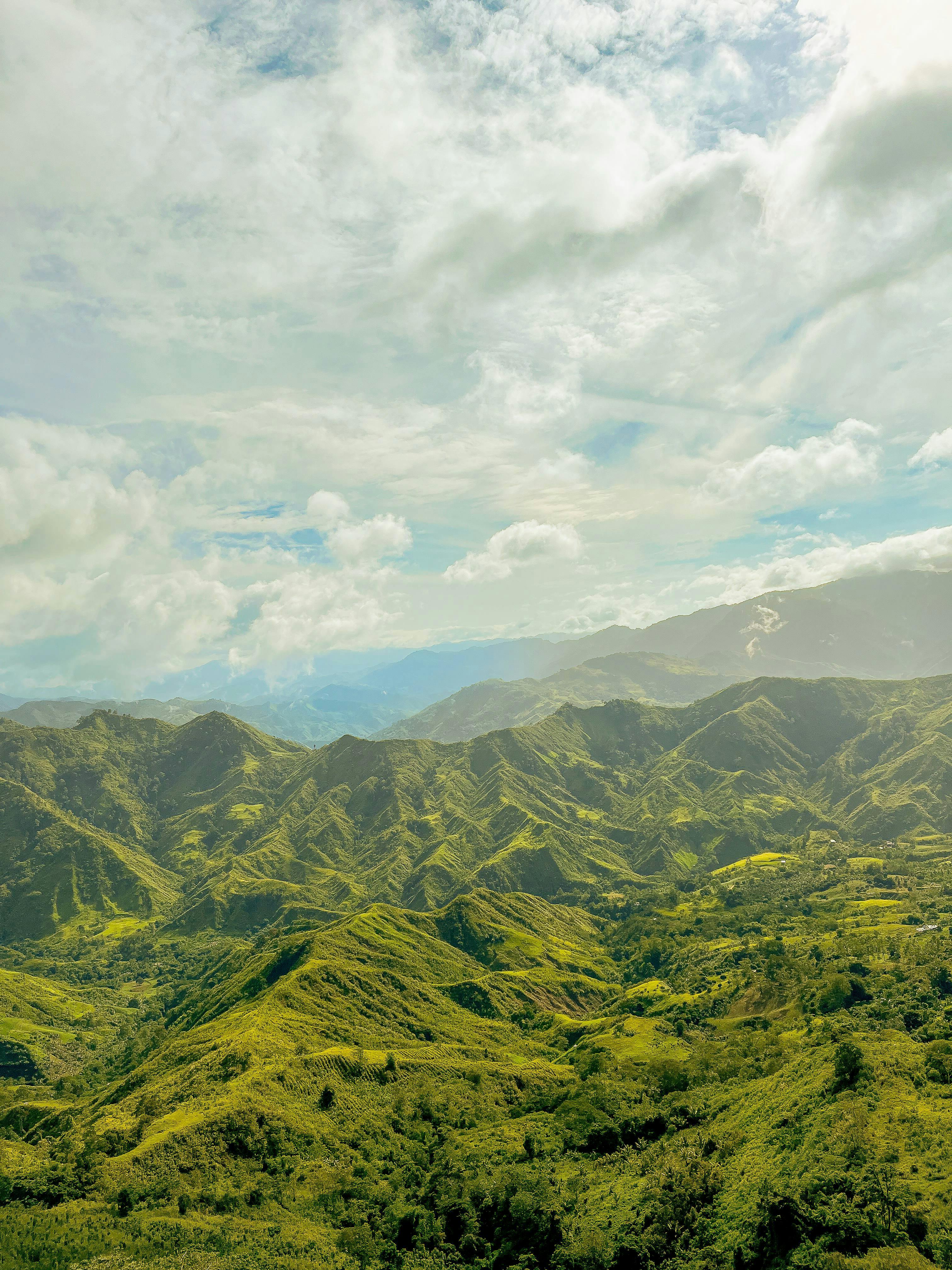 Breathtaking aerial view of rolling green mountains under a cloudy sky.