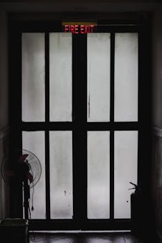 消防出口门的黑色轮廓图像带有可见标牌，营造出喜怒无常的氛围