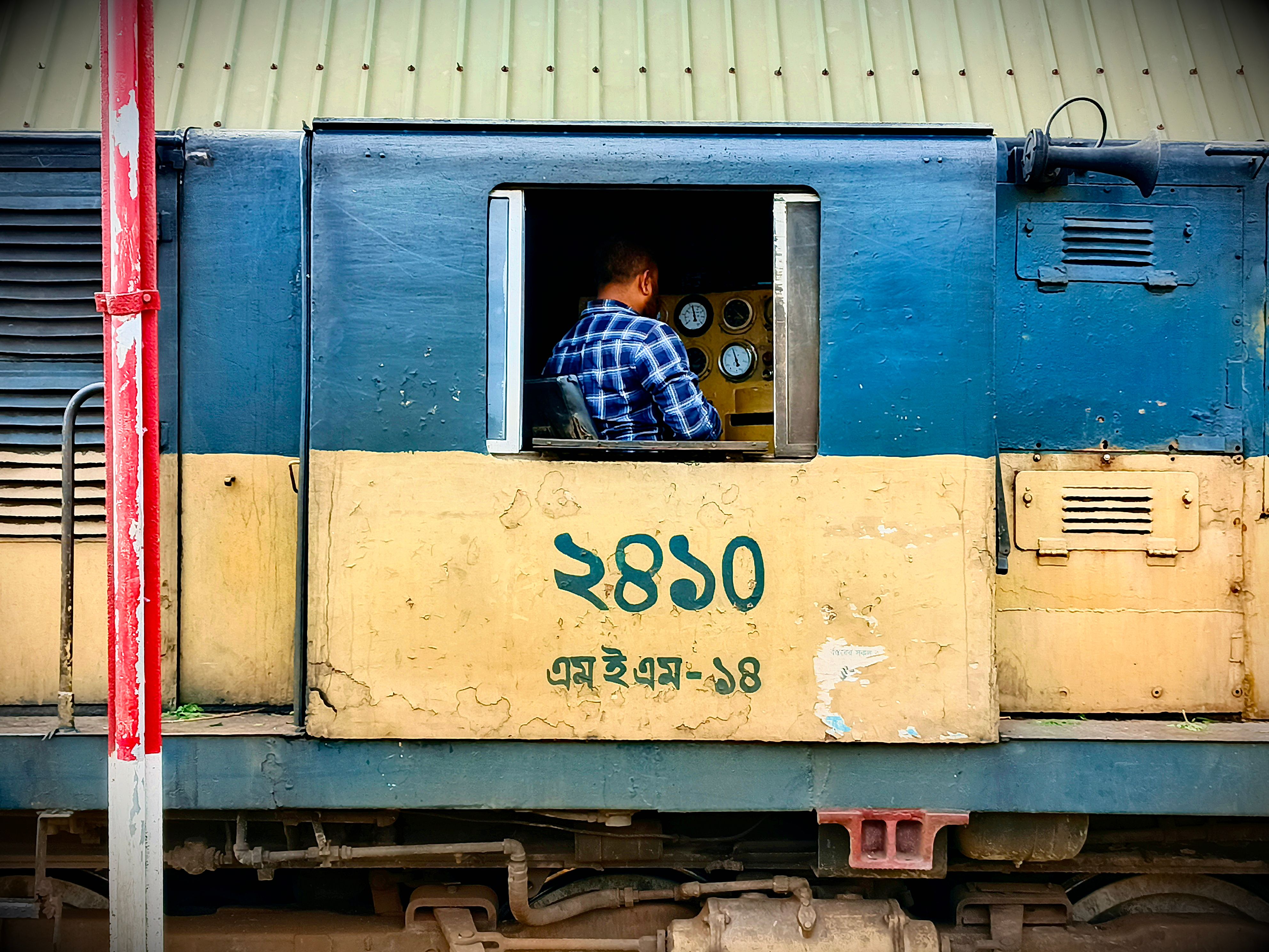 A conductor operating a train, focusing on control panel inside the locomotive cabin.