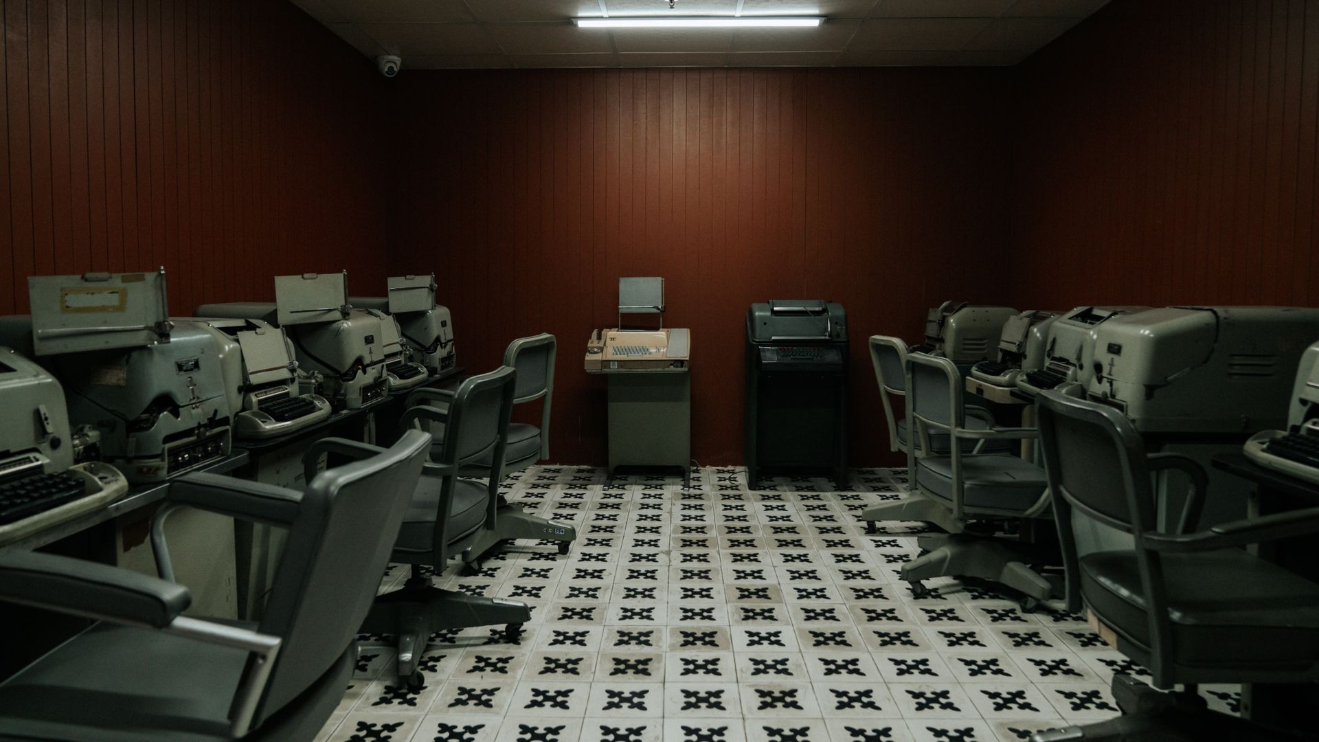 A vintage office room filled with old typewriters and chairs, evoking a 1940s-1960s era ambiance.