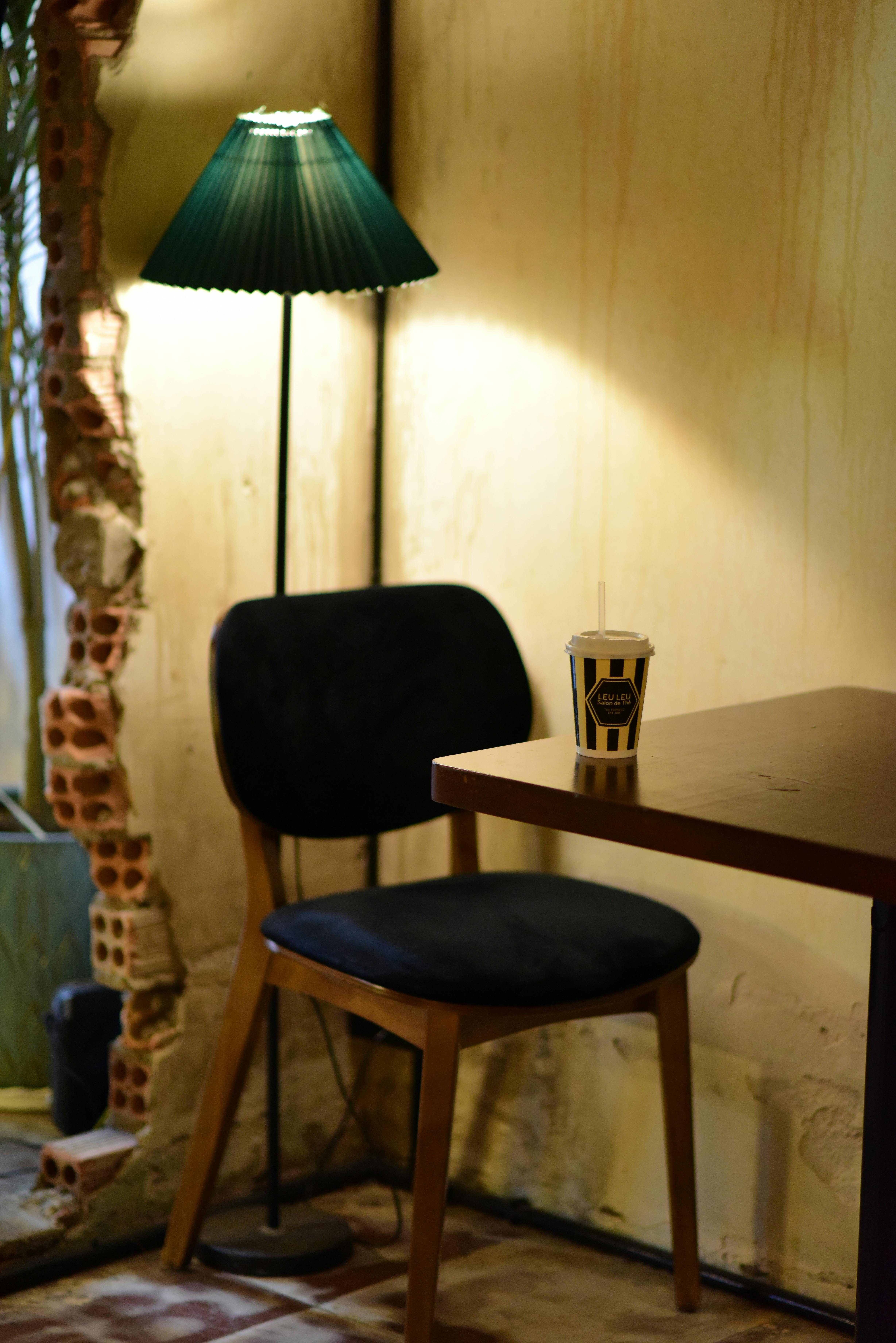 Gratuit Atmosferă intimă de cafenea, cu scaun, masă și iluminare ambientală de la o lampă de podea. Fotografie de stoc