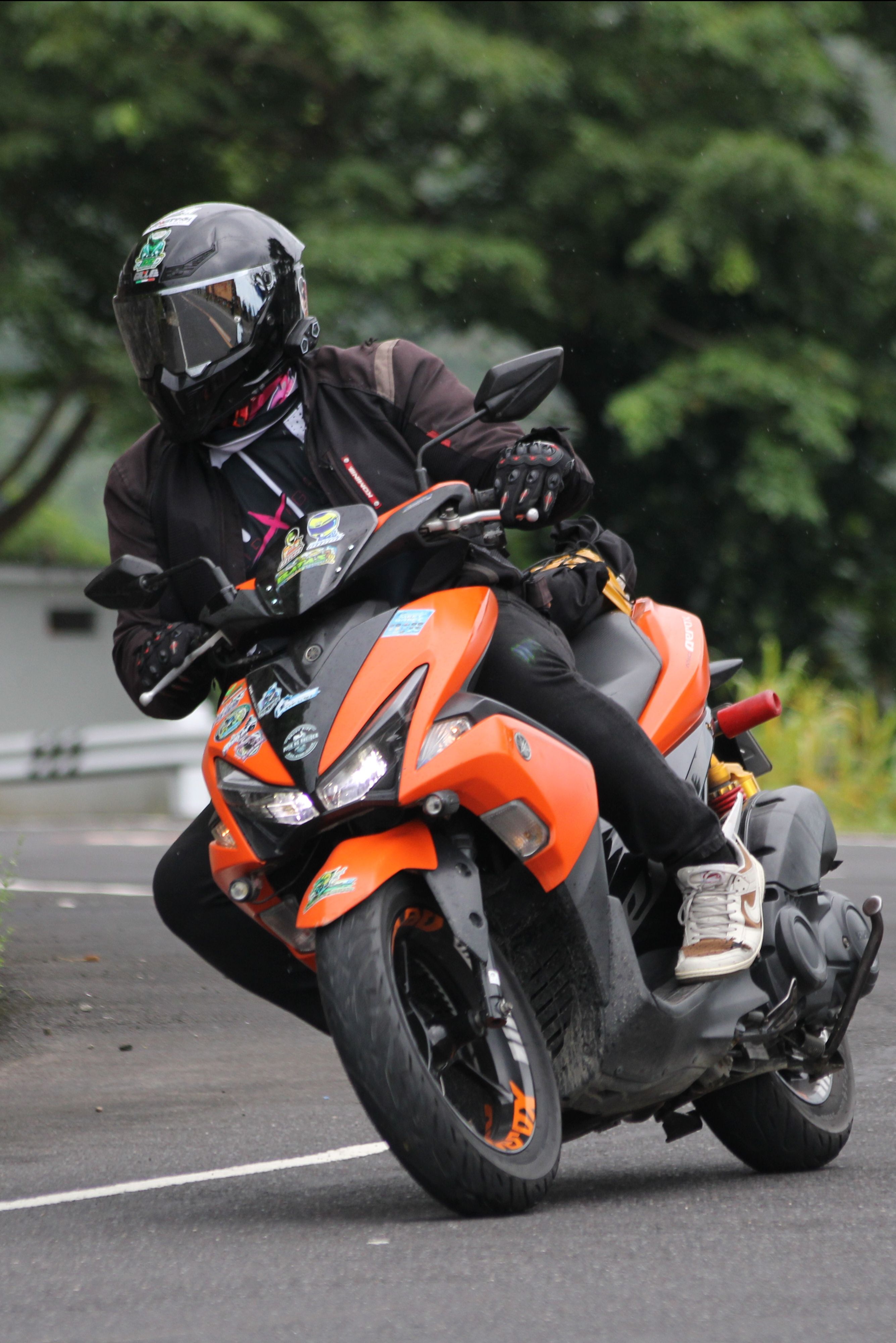 A motorcyclist riding an orange bike on a winding road in Sagnay, Bicol, Philippines.