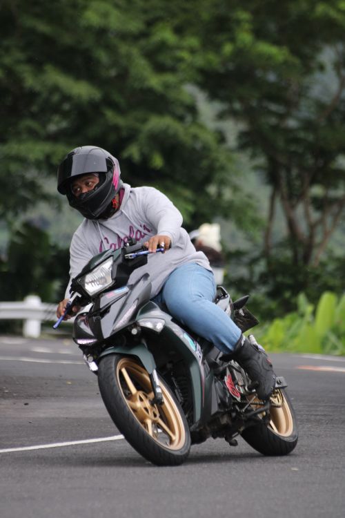 Free Motorcyclist leans into a turn on a scenic outdoor road showcasing skill and balance. Stock Photo