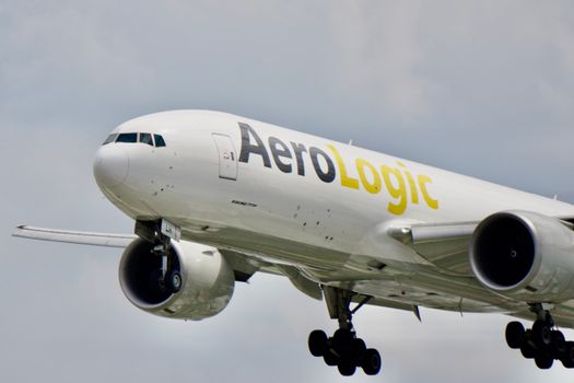 Close-up image of an AeroLogic Boeing 777 aircraft in flight against a cloudy sky.