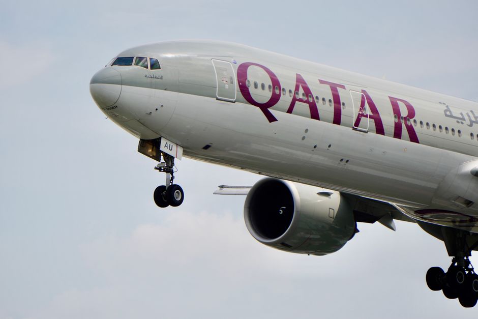 A close-up view of a Qatar Airways airplane's landing gear during flight against the sky.