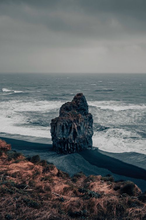 Free Dramatic sea stack in Iceland with waves crashing under a moody sky. Stock Photo
