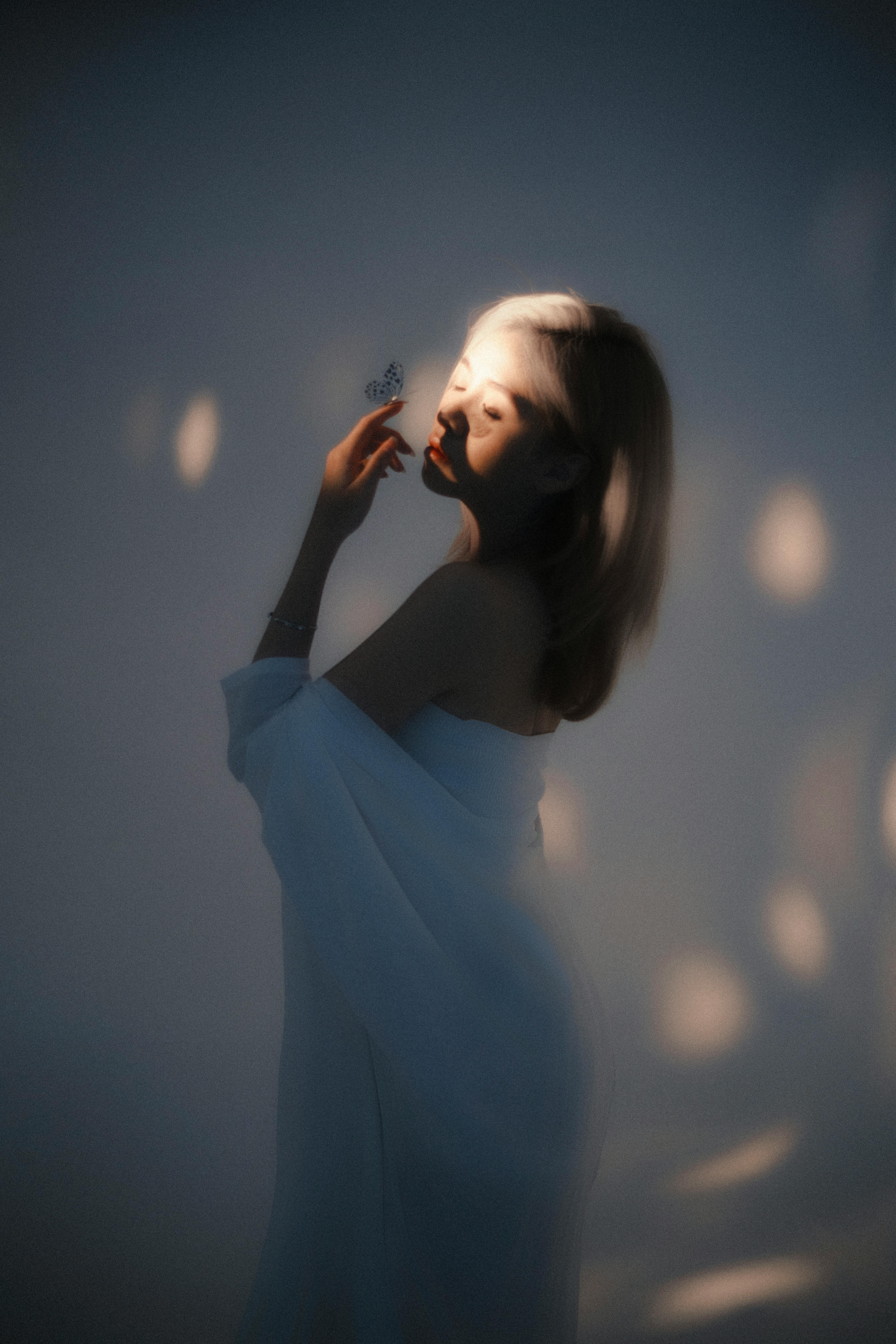A serene portrait of a woman interacting with a butterfly in a dreamy light setting.