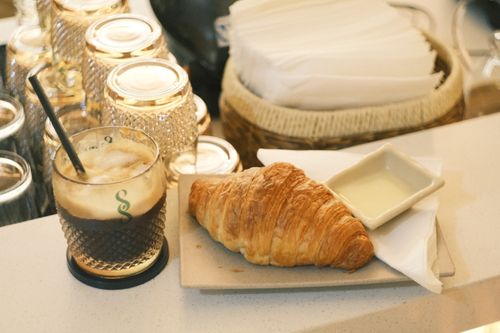Free Delicious croissant with creamy dip and iced coffee set on a cafe counter. Stock Photo