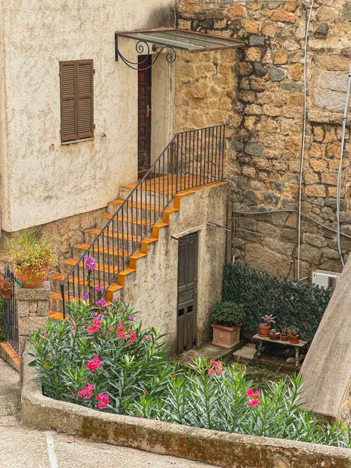 Free Rustic staircase with colorful flowers and stone wall, creating a charming outdoor scene. Stock Photo