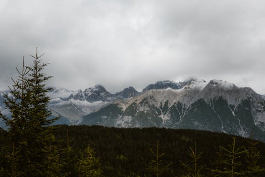 A breathtaking view of a snow-capped mountain range under a cloudy sky.