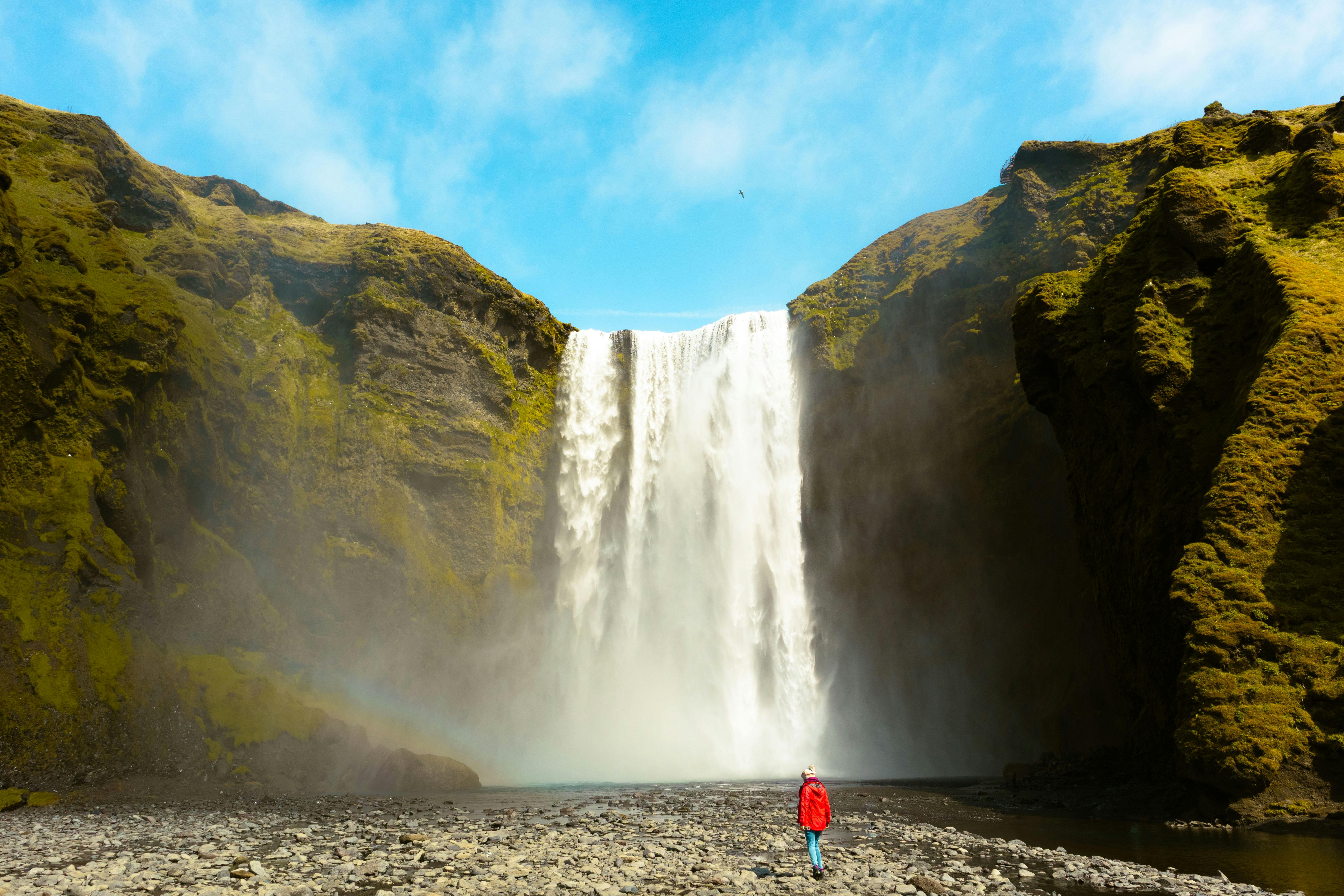 woman standing alone in front of a waterfall in Iceland looking peaceful
