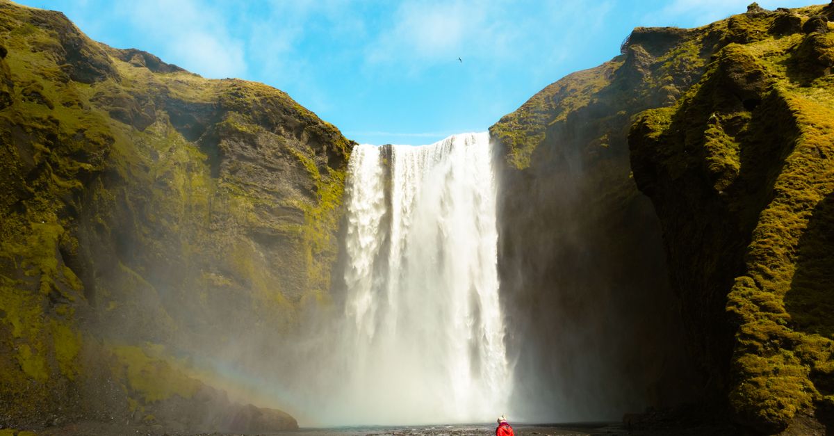 woman standing alone in front of a waterfall in Iceland looking peaceful