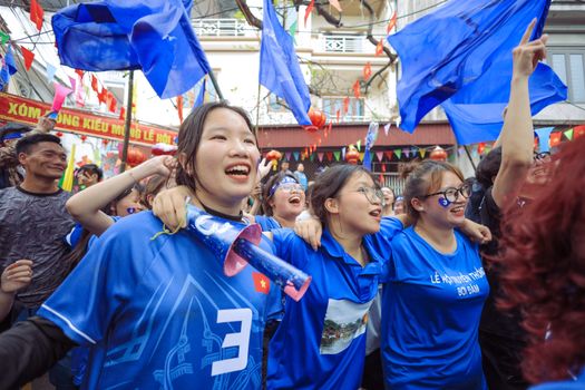 Joyful crowd celebrating with blue flags on a lively street.