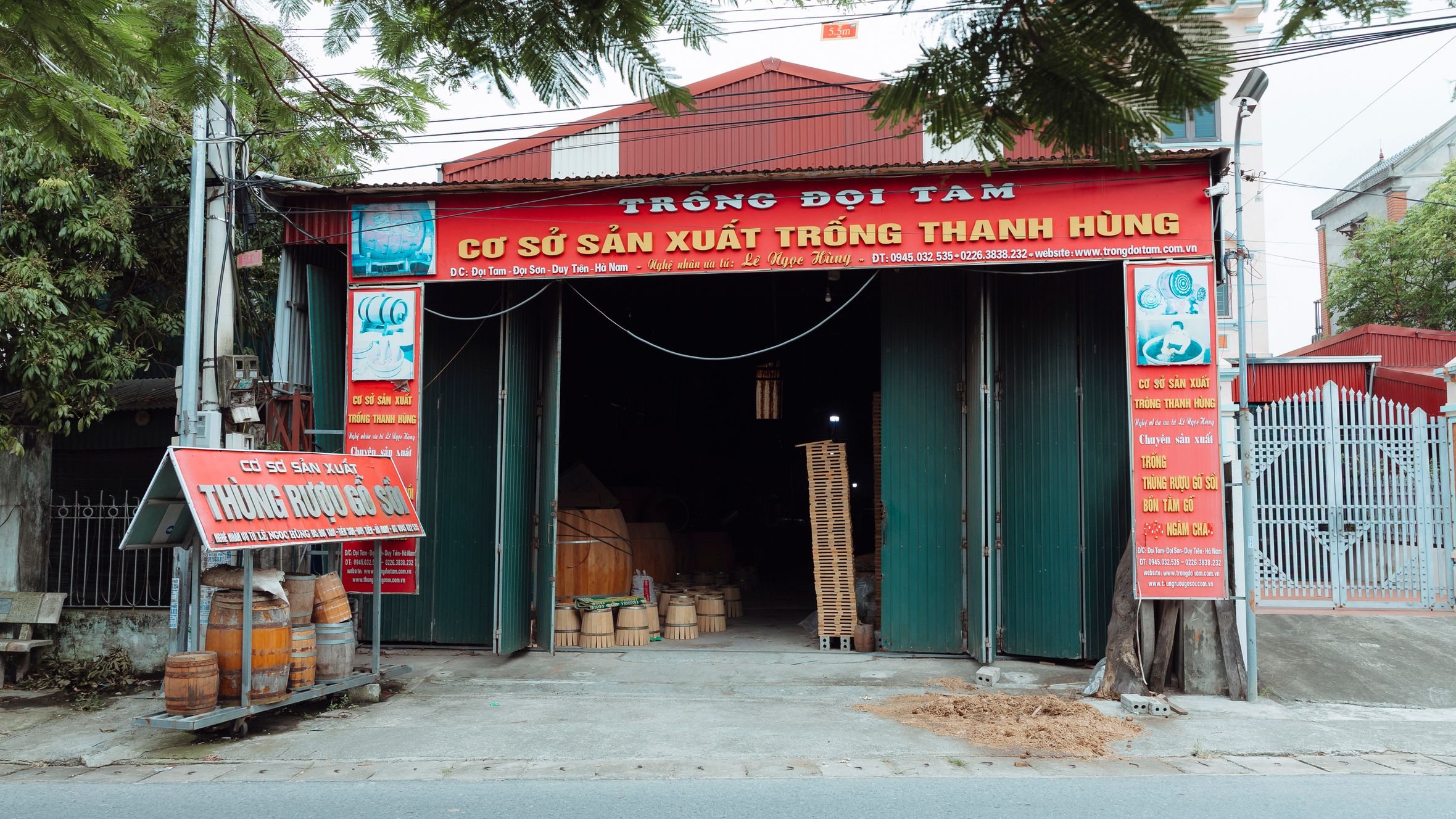 Front view of a traditional drum workshop in Duong Son, featuring wooden barrels and vibrant signage.