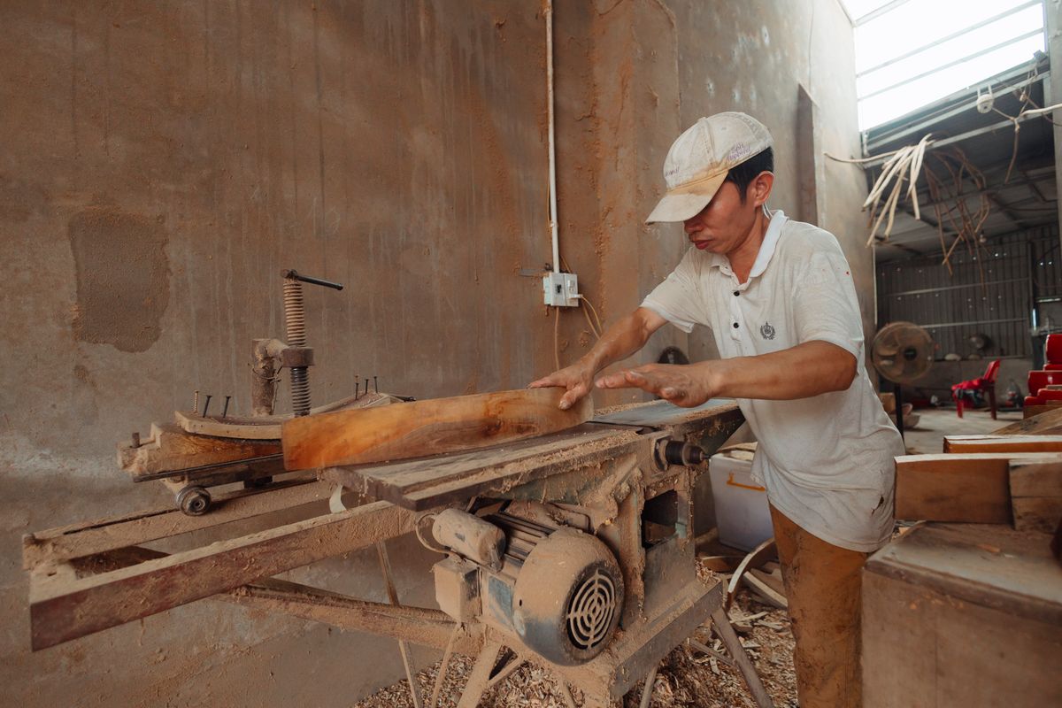 Carpenter cutting wood on an industrial saw in a workshop