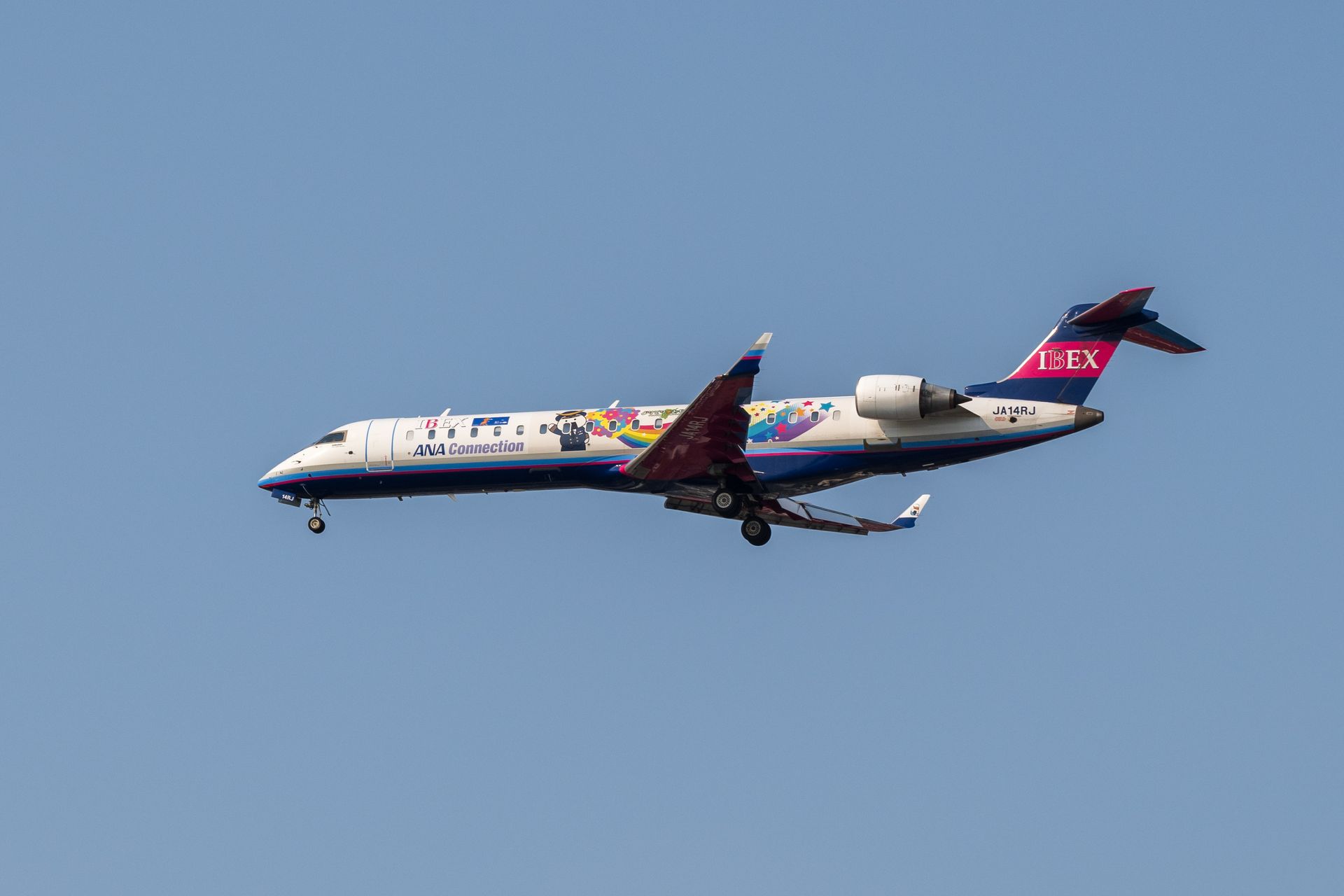 A vibrant ANA Connection airplane soaring against a clear blue sky, capturing mid-air travel.