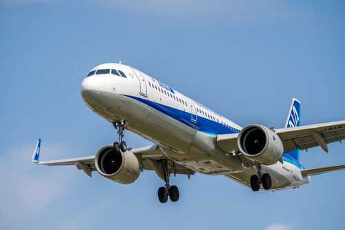 Free A commercial airplane in mid-flight with landing gear down against a clear blue sky. Stock Photo