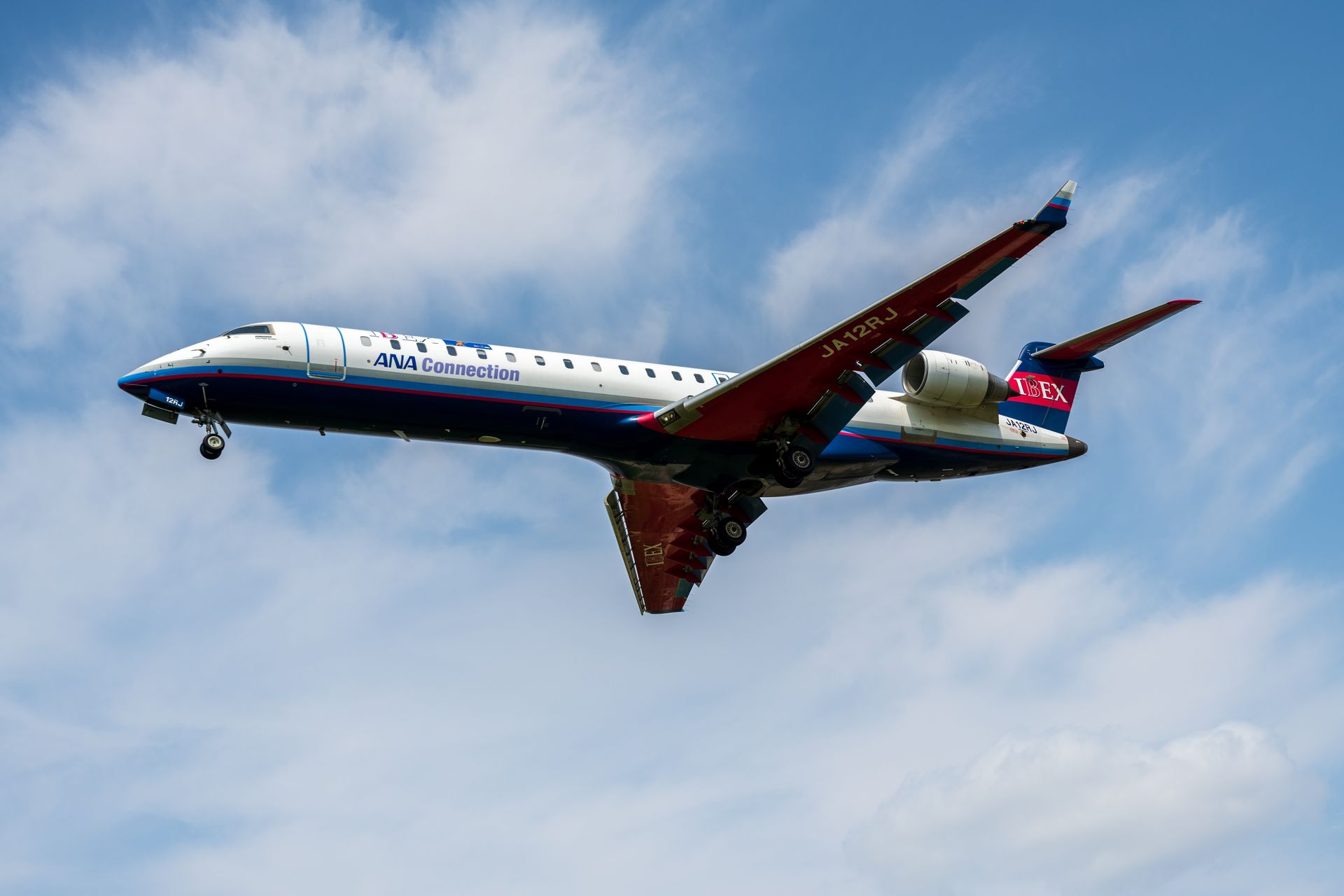 A mid-air shot of an ANA Connection jet with blue and white livery soaring through a clear sky.