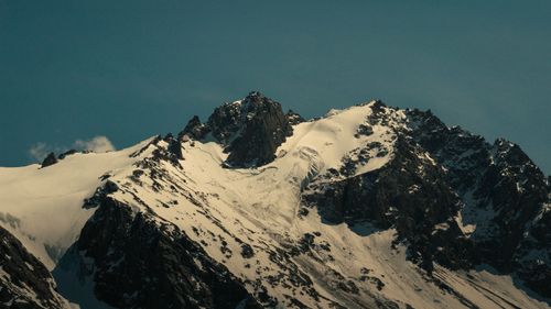 Free Majestic snow-covered mountain peaks illuminated under a clear blue sky. Perfect for nature and travel themes. Stock Photo