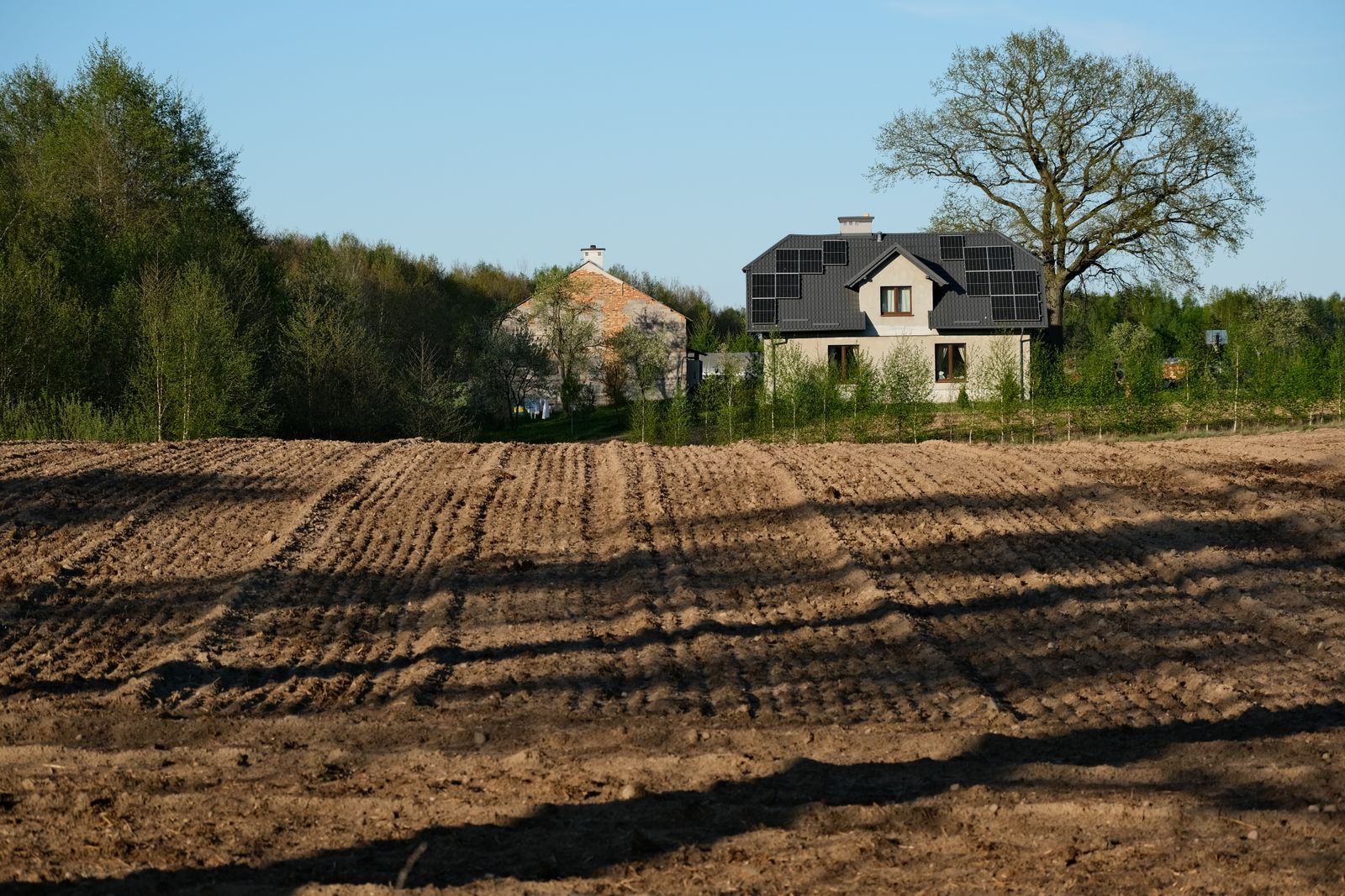 Sustainable countryside home with solar panels beside a spring field