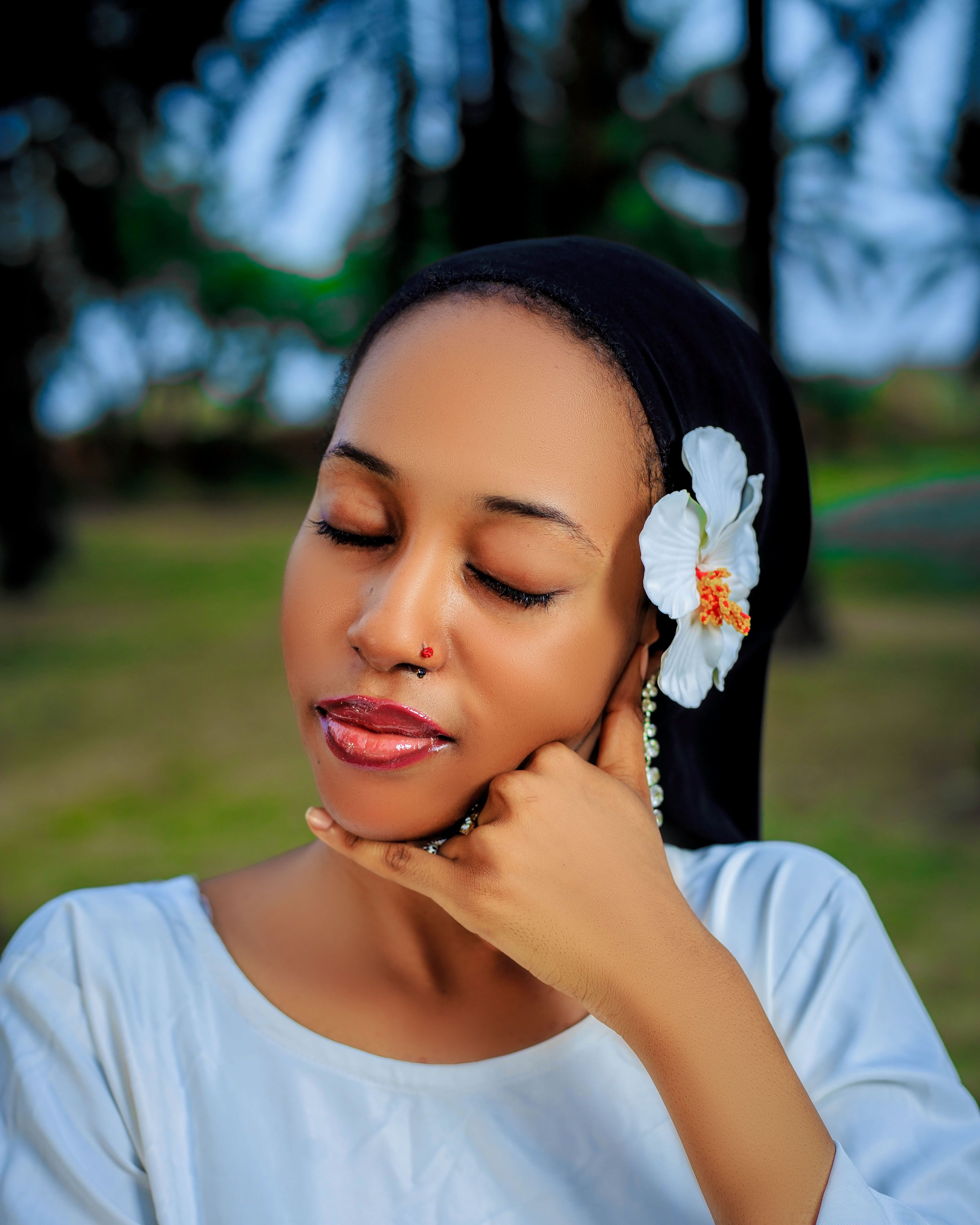 A tranquil outdoor portrait of a woman with a white flower in her hair.