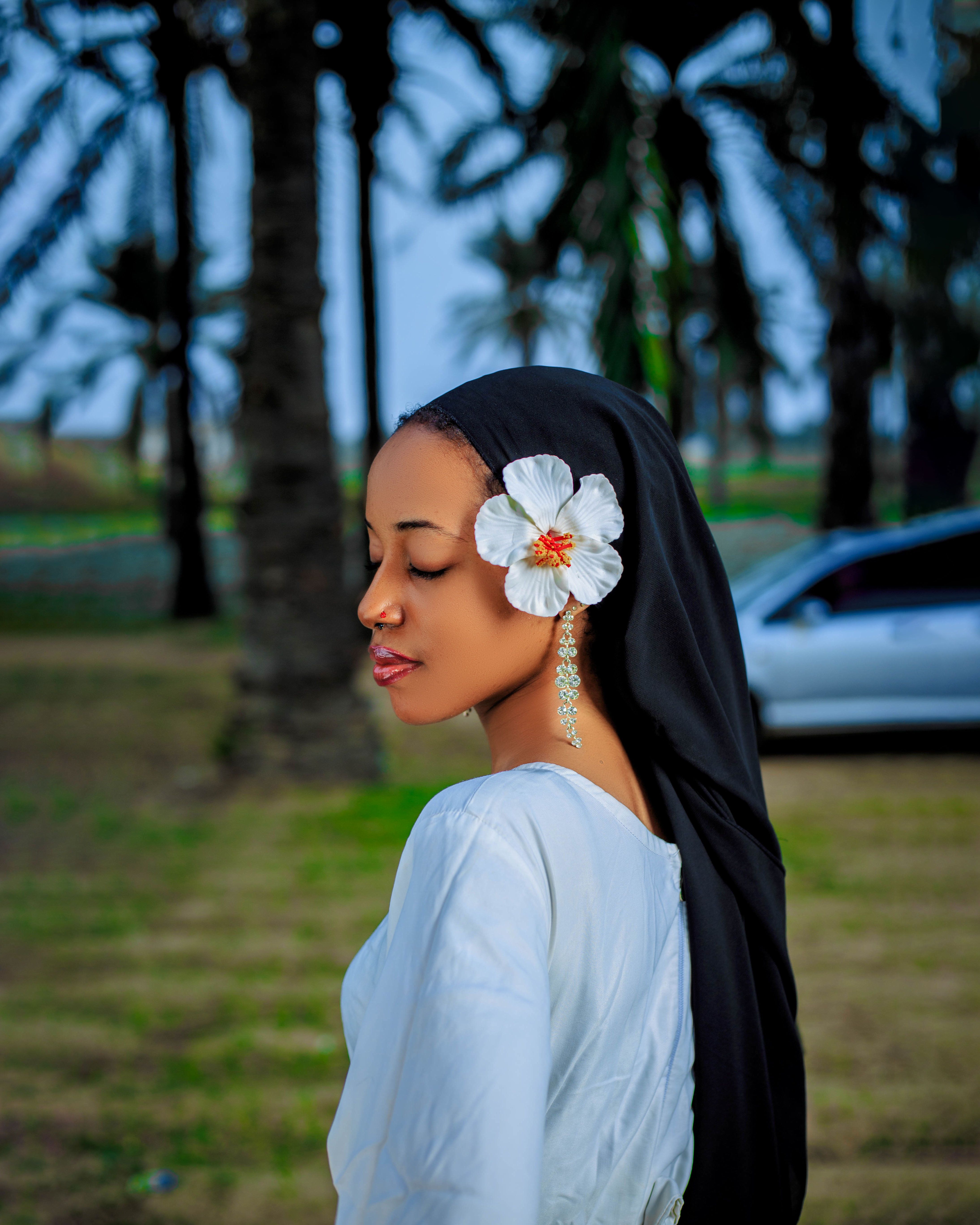 Peaceful image of a woman in hijab with a flower, set in nature.