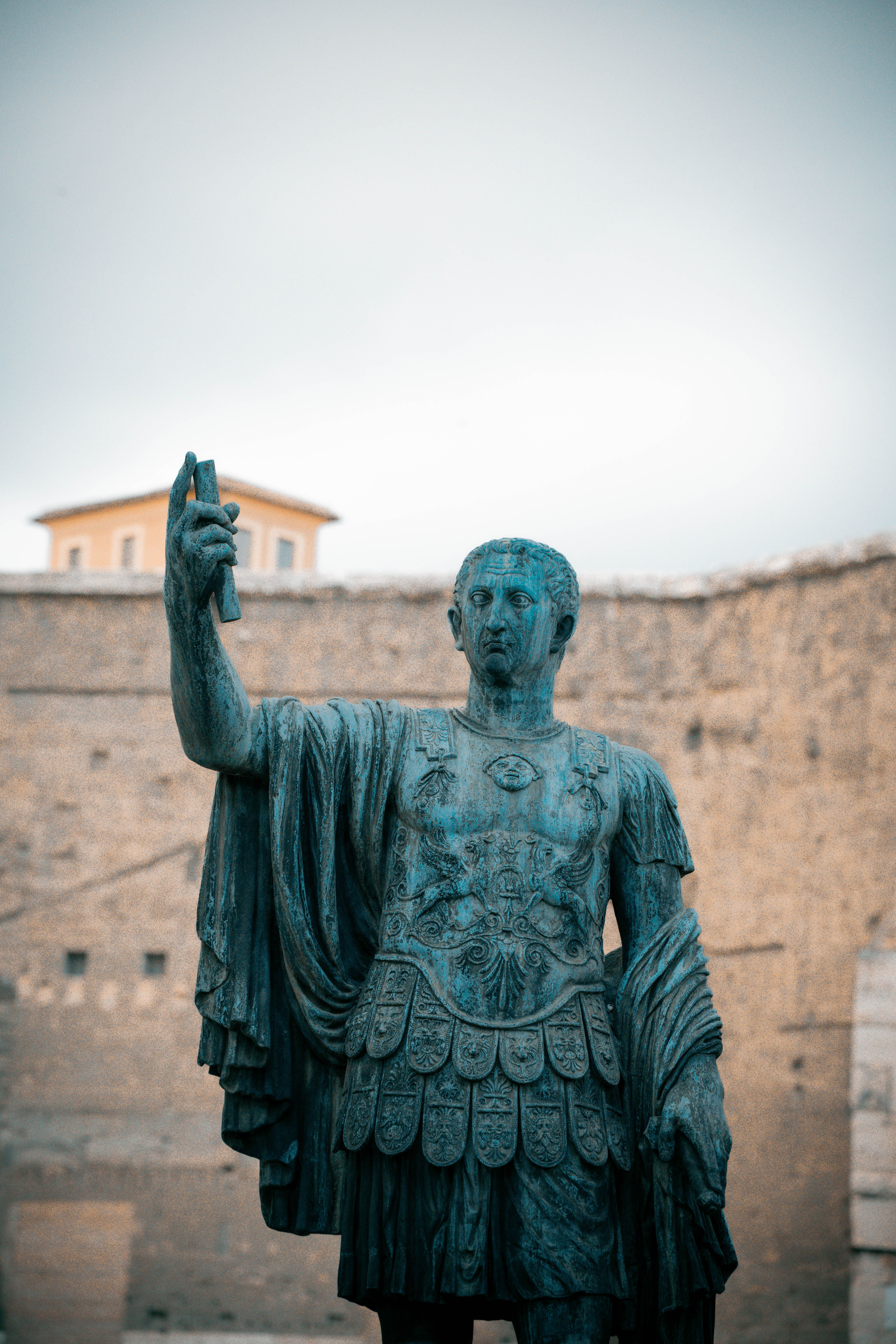 A striking statue of Julius Caesar situated against the backdrop of ancient Roman architecture.