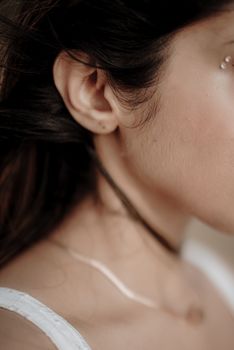 Close-up of a woman's ear and pearl earring, showcasing minimalist design.