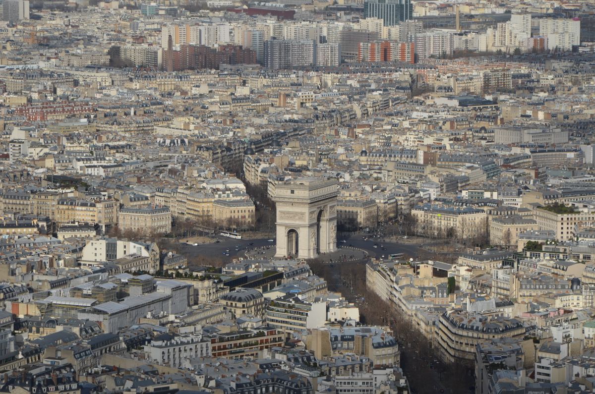 Aerial view of the Arc de Triomphe with the Parisian cityscape stretching in every direction
